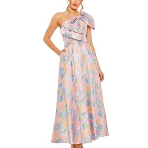 A woman in a One Shoulder Embroidered Floral A Line Dress, featuring a large bow and pockets, stands against a white background wearing neutral high-heeled shoes.