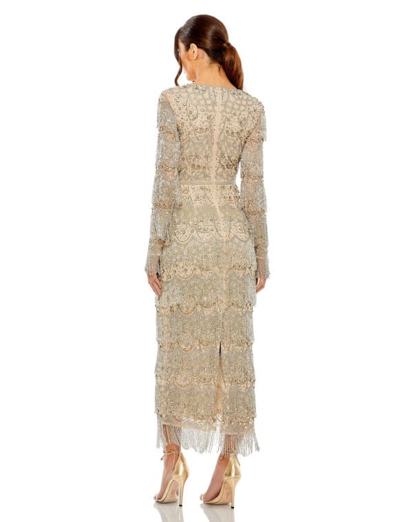 A woman in a V Neck Beaded Fringe Embellished Dress and high heels stands with her back to the viewer against a white background.