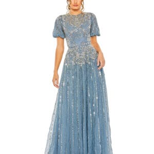 A woman in a high neck puff sleeve embellished A-line gown with intricate silver embroidery, standing against a white background.