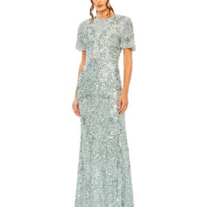 A woman wearing a Flutter Sleeve Sequin High Neck Gown, shimmering in silver and reaching the floor, stands against a white background.